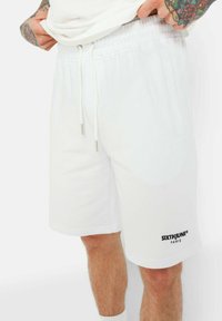 Shorts bianchi in cotone con cintura elastica dotata di stringa e tasche laterali. Logo nero "SIXTHJUNE PARIS" sulla gamba sinistra.