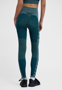 Leggings da workout in teal con una cintura alta, pannelli testurizzati e lisci, sezioni in rete e accenti scuri a contrasto lungo i lati.