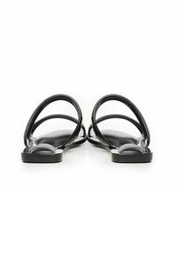 Sandales plates noires avec une finition lisse et brillante, bout ouvert, et plusieurs lanières incurvées pour un meilleur maintien. Semelle intérieure texturée et semelle plate.
