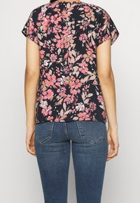 Květinová blůza s krátkými rukávy, s námořnickým pozadím, růžovými a krémovými květinami a uvolněným střihem. Nosit s tmavými denimovými džíny.