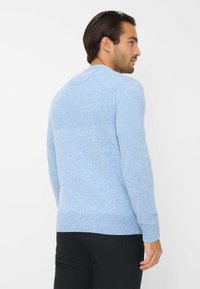 Helles, blaues Strickpullover mit strukturiertem Finish, ausgestattet mit einem runden Ausschnitt und gerippten Bündchen, kombiniert mit schwarzen Hosen.