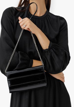 Czarna torebka z lakierowanej skóry ekologicznej z srebrnym łańcuszkiem, o prostokątnym kształcie i trzech poziomych panelach.
