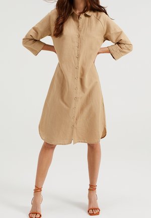 Vestido camisero de lino beige con cierre de botones en la parte delantera, cuello, mangas tres cuartos y aberturas laterales en el dobladillo.