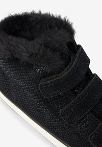 Black high-top sneakers featuring a textured surface with a diamond pattern, fuzzy black trim, and two Velcro straps for closure.