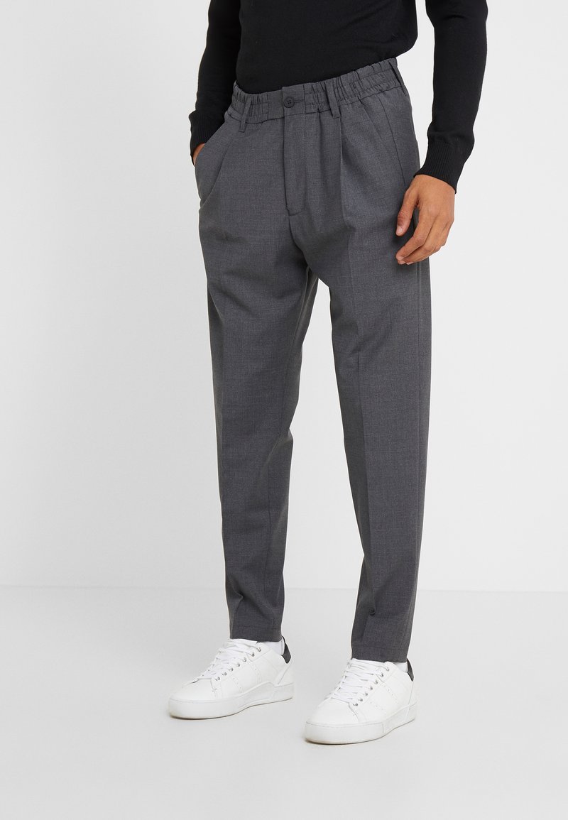 Grau, tapered Hosen mit einem elastischen Bund und Knopfverschluss. Verfügt über seitliche Taschen und ein strukturiertes, leichtes Material. Kombiniert mit weißen Sneakern.