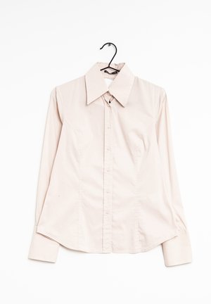 Light beige long-sleeve button-up shirt with wide collar hanging on black hanger against white background.