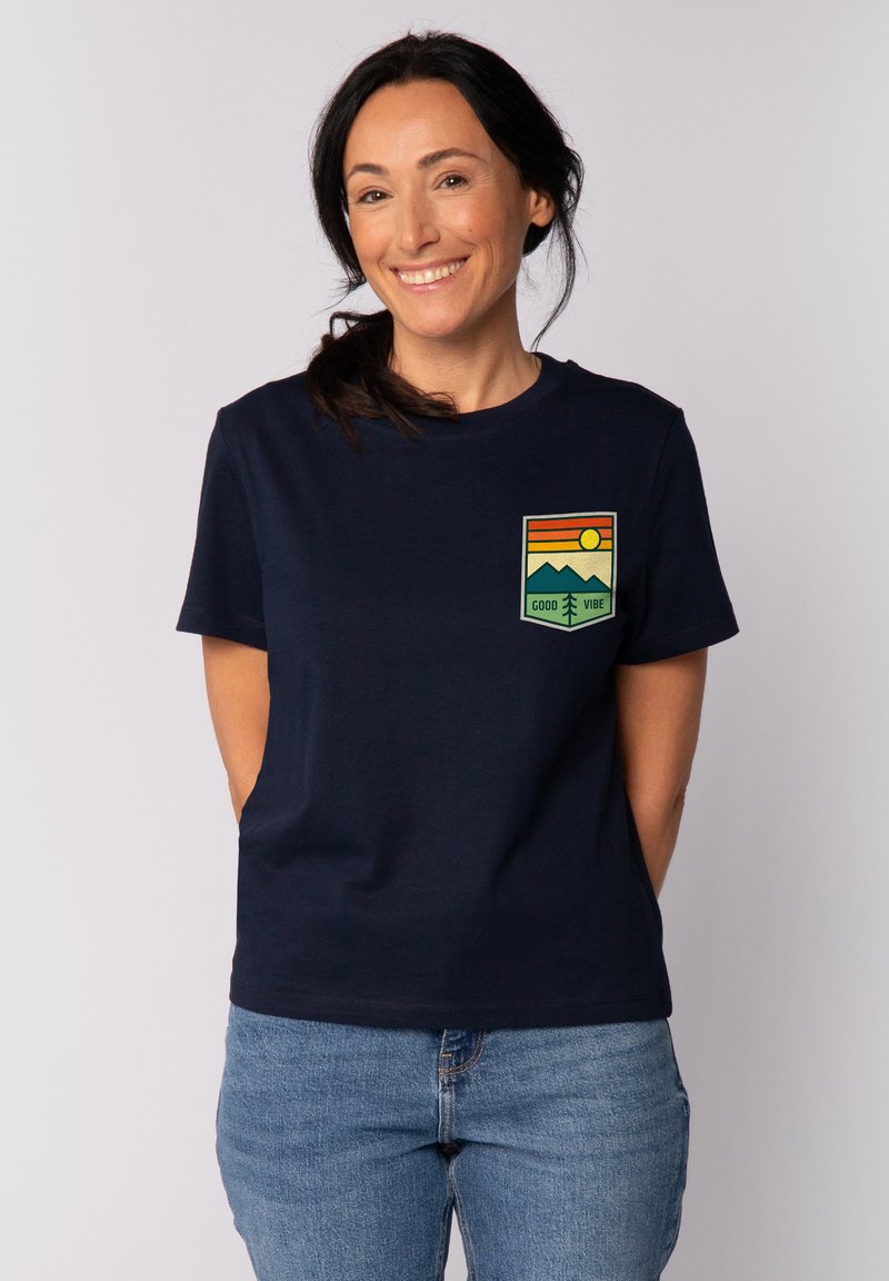 Navyblauwe katoenen t-shirt met een grafisch voorvak waarop bergen, een zon en de tekst "GOOD VIBE" in groene, oranje en gele tinten.