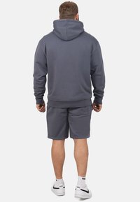 Grijze hoodie met een trekkoordcapuchon, gecombineerd met grijze shorts. Gemaakt van zacht materiaal, met een relaxed fit en geribde boorden.