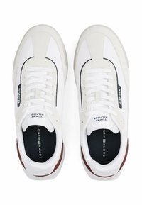 Sneaker atletiche bianche con una combinazione di texture liscia e scamosciata, con accenti neri e bordeaux, lacci e una soletta con marchio.