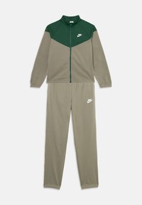 Nike zip-up treniruočių kostiumas alyvuogių ir žaliame atspalvyje, turintis aukštą apykaklę, kontrastingo rašto dizainą, elastingus rankogalius ir logotipą krūtinėje bei ant kelnių.