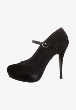 Chaussure à talon haut noire en suede, avec un bout rond, une plateforme en cuir laqué brillant et une bride à la cheville avec une boucle circulaire.