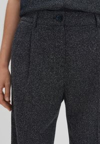 Pantalons bleu marine foncé avec un tissu texturé. Dotés d'une fermeture à bouton et de plis sur le devant. Le matériau présente des nuances légères subtiles pour un détail supplémentaire.