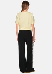 Light yellow short-sleeve t-shirt and black wide-leg pants with white side stripes featuring a leopard print design.