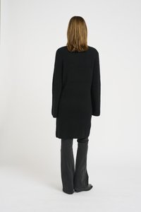 Maglione oversize nero in maglia con maniche lunghe, finitura testurizzata e taglio dritto, abbinato a jeans in denim scuri a zampa.