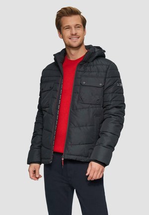 Black padded jacket with hood, featuring two chest pockets, zip closure, and red inner lining, worn over a red sweater.