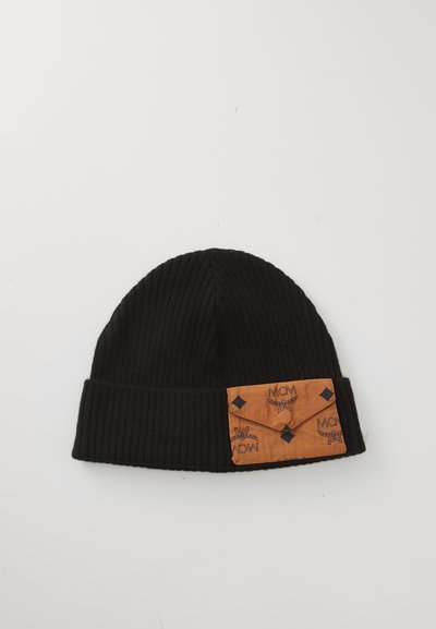 Bonnet en maille côtelée noire avec un patch en cuir beige affichant un motif de logo répété et des accents en forme de losange noirs à l'avant.