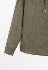 Greenish-brown long-sleeve shirt featuring a buttoned placket, made from a textured fabric, displayed against a white background.