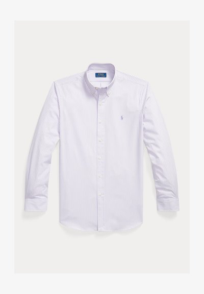 Biela košeľa s dlhým rukávom a zapínaním na gombíky, tenkými levanduľovými vertikálnymi pruhmi, špicatým golierom a malým vyšívaným logom na hrudi.