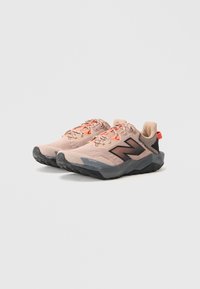 Pair of light pink and grey athletic sneakers with black soles and orange accents, angled to show sides and front details.