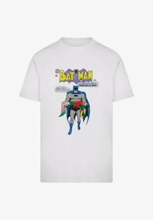 White cotton T-shirt featuring a comic-style print of Batman carrying Robin. Text includes "BATMAN" and "ROBIN DIES AT DAWN!" in bold colors.