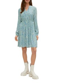 Abito azzurro chiaro con motivo astratto verde e blu, vita arricciata, maniche lunghe e colletto. Abbinato a stivali bianchi alla caviglia.