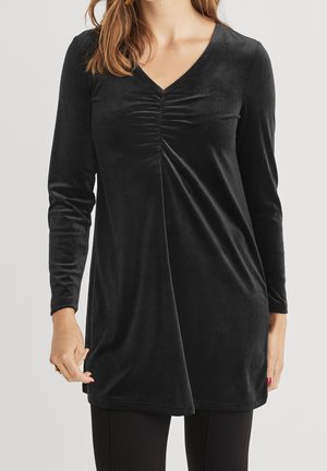 Black long-sleeve velvet tunic with ruched detail at the V-neck, worn with black pants on a person against a plain background.