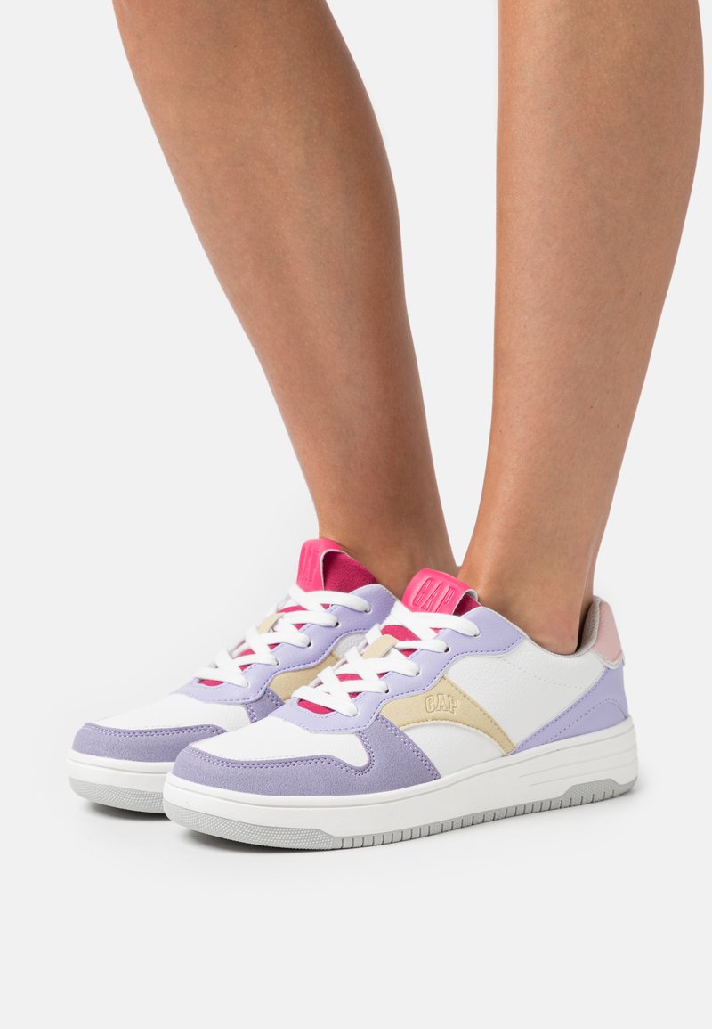 Zapatillas púrpuras, blancas y rosas que presentan una mezcla texturizada de cuero y gamuza, con un logo en el lateral y cordones de color contrastante.