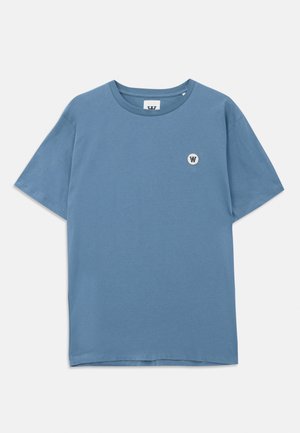 Kék pamut póló kerek nyakkivágással, rövid ujjakkal és egy kis kerek logóval, amelyen egy "W" látható a bal mellső részen.