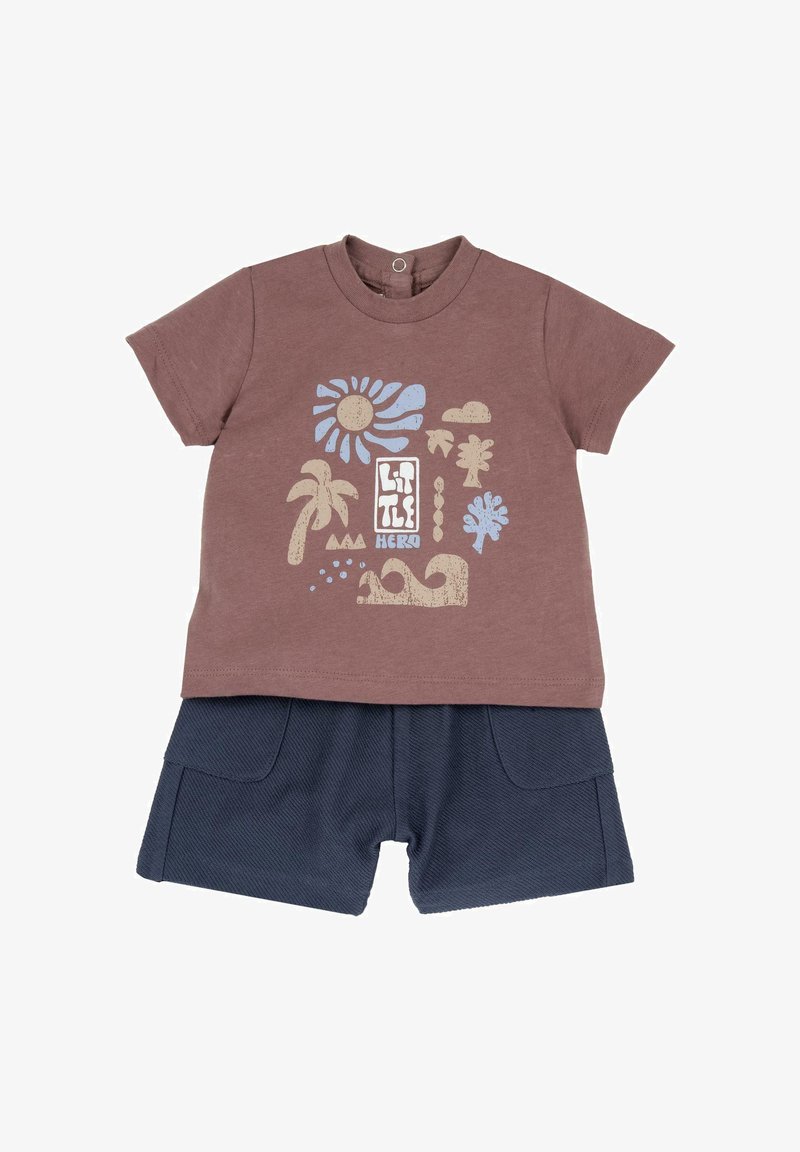 Tenue pour tout-petit avec un t-shirt marron à motif représentant le soleil, des palmiers, des nuages et des vagues, associée à un short bleu marine texturé avec des poches avant.
