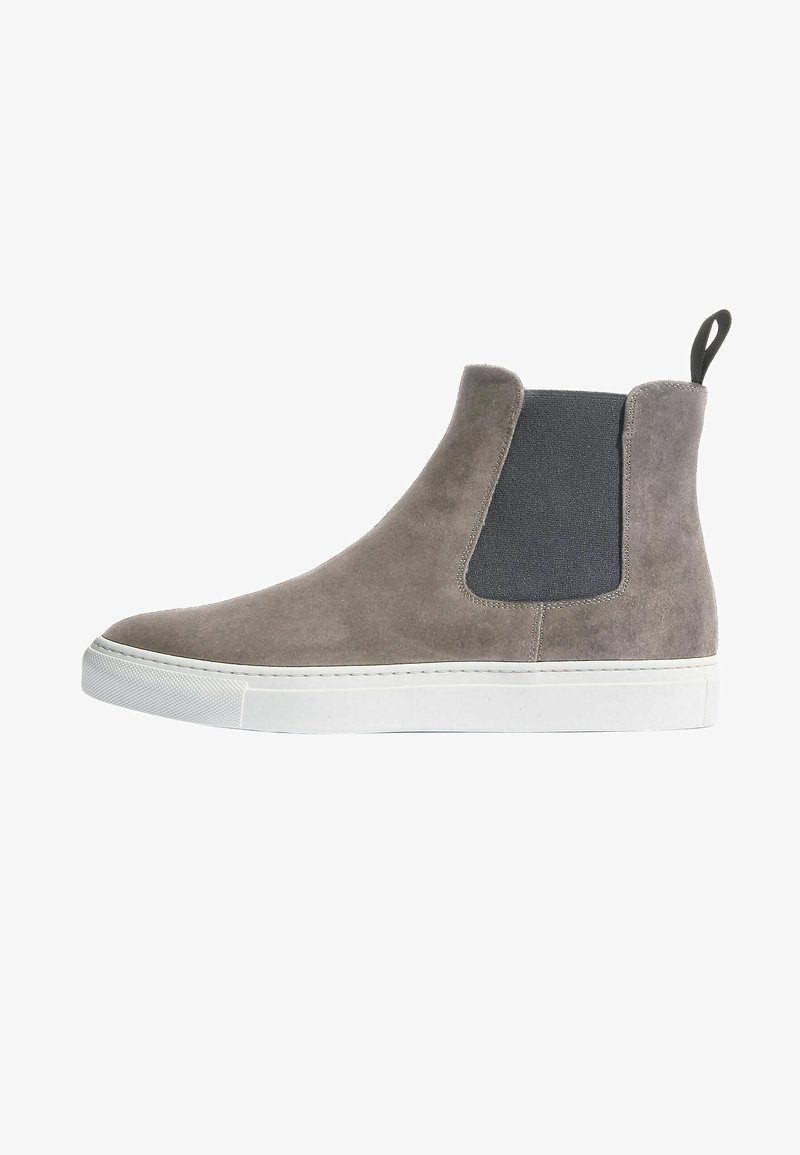 Botines de ante gris con panel lateral elástico negro, suela de goma blanca y tira en la parte posterior; acabado suave y líneas limpias.