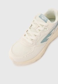 White sneakers with mesh and suede materials, featuring light blue accents, round toe, and textured laces. Branding appears on the tongue.