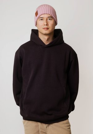 Ciemnofioletowa bluza z kapturem z przednią kieszenią oraz jasnoróżowa prążkowana czapka z daszkiem, ozdobiona skórzaną metką. Prosty design i miękka faktura.