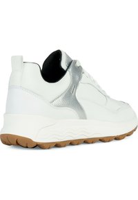 Zapatilla blanca con un acento plateado texturizado en el talón, una suela de goma resistente y un corte superior suave con un diseño de punta redonda.