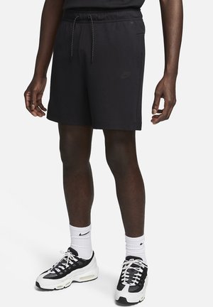 Czarne szorty sportowe wykonane z miękkiego materiału, z elastyczną talią i sznurkiem do regulacji, kieszeniami po bokach oraz subtelnym detalem z logo.