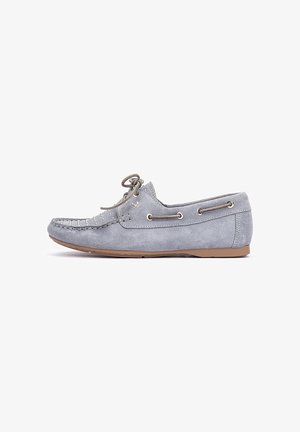 Mocassin pour homme en daim gris clair, avec coutures moc toe, lacets sur l'avant, détails de lacets sur le côté, et semelle en caoutchouc plate couleur beige clair.
