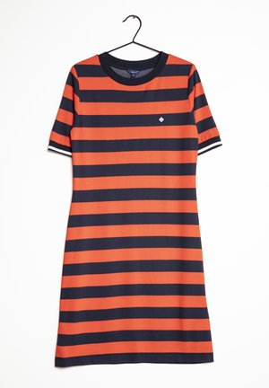 Robe à manches courtes avec des rayures horizontales noires et orange vif suspendue sur un cintre noir sur fond blanc.