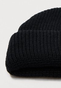 Čierna pletená čiapka s textúrovaným, rebrovaným vzorom a prehnutým okrajom, vyrobená z jemného a pružného materiálu.
