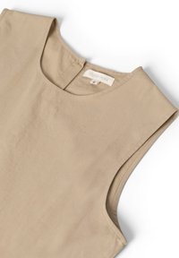 Haut sans manches beige en tissu lisse ; présente un col rond et une petite ouverture au dos. L'étiquette indique "STUDIO FEDER," taille S.