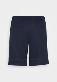 Marinblå träningsshorts tillverkade av ett mjukt, elastiskt tyg. Har en elastisk midja och en något längre passform med fållade kanter.