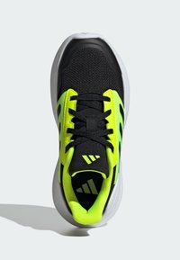 Black and neon yellow athletic shoe with a mesh upper, padded collar, and rubber sole. Features textured laces and branding on the tongue.