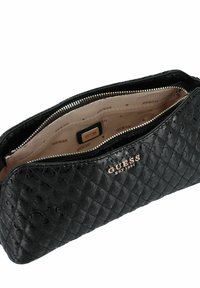 Pochette nera in ecopelle trapuntata con chiusura a zip, hardware in tonalità oro e interno beige con logo "GUESS" ripetuto.