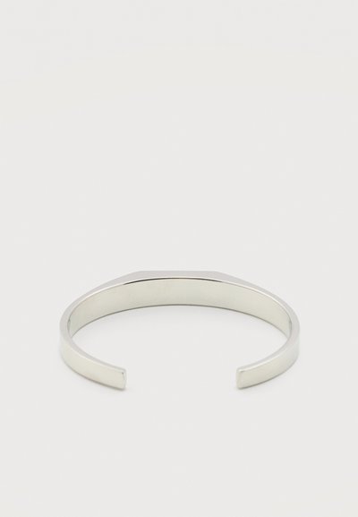 Μινιμαλιστικό ασημένιο περιδέραιο με ανοιχτές άκρες, λεία γυαλιστερή επιφάνεια και ελαφρώς καμπυλωτό σχήμα σε απλό λευκό φόντο.