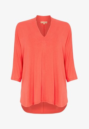 Túnica coral con escote en V, mangas tres cuartos y un corte fluido con un dobladillo trasero más largo; fabricada en un tejido ligero.