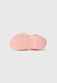 Sola de sandália Crocs rosa em tamanho infantil com padrão de textura no fundo branco liso.