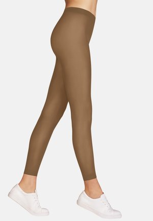 Bruine leggings van rekbaar materiaal, met een gladde textuur en een hoge tailleband, gecombineerd met witte sneakers.