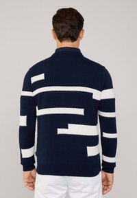 Maglione blu navy con blocchi bianchi a motivo, colletto e polsini a coste, lavorazione a maglia testurizzata e una vestibilità comoda. La vista posteriore mette in evidenza il suo design moderno.