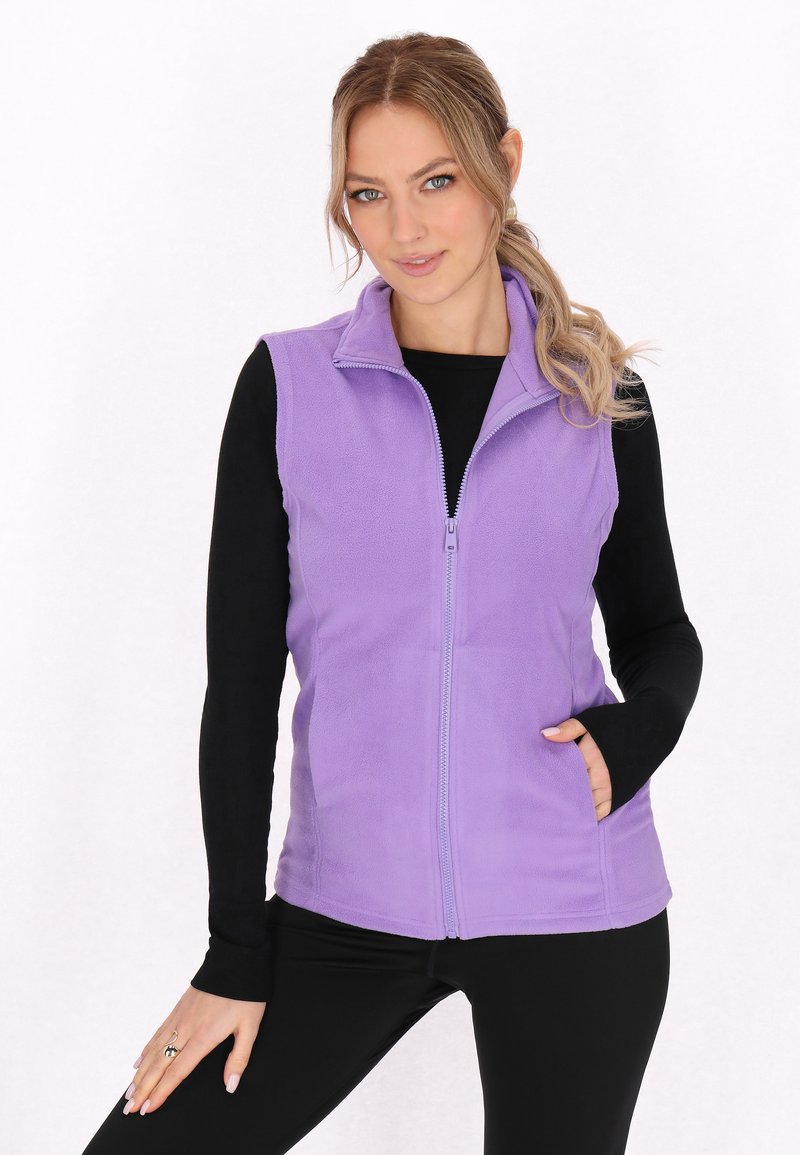 Gilet in pile viola con zip frontale, colletto a manica, e tasche laterali, indossato sopra una maglietta nera a maniche lunghe, caratterizzato da una texture morbida.