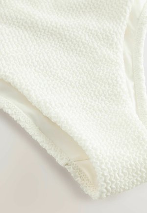 Costume da bagno bianco texturizzato con un design in tessuto smock, foderato morbido e bordi arricciati per un tocco di dettaglio e comfort.