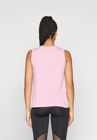 Ροζ αθλητικό τοπ χωρίς μανίκια με στρογγυλή λαιμόκοψη, απαλή υφή και άνετη εφαρμογή. Η πίσω πλευρά έχει ελάχιστη λεπτομέρεια ραφής και μια ετικέτα.