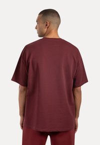 Bordeaux korte mouwen t-shirt in een relaxed fit, met een ronde hals en zachte, gladde stof. De achterkant heeft een eenvoudige uitstraling zonder versieringen.